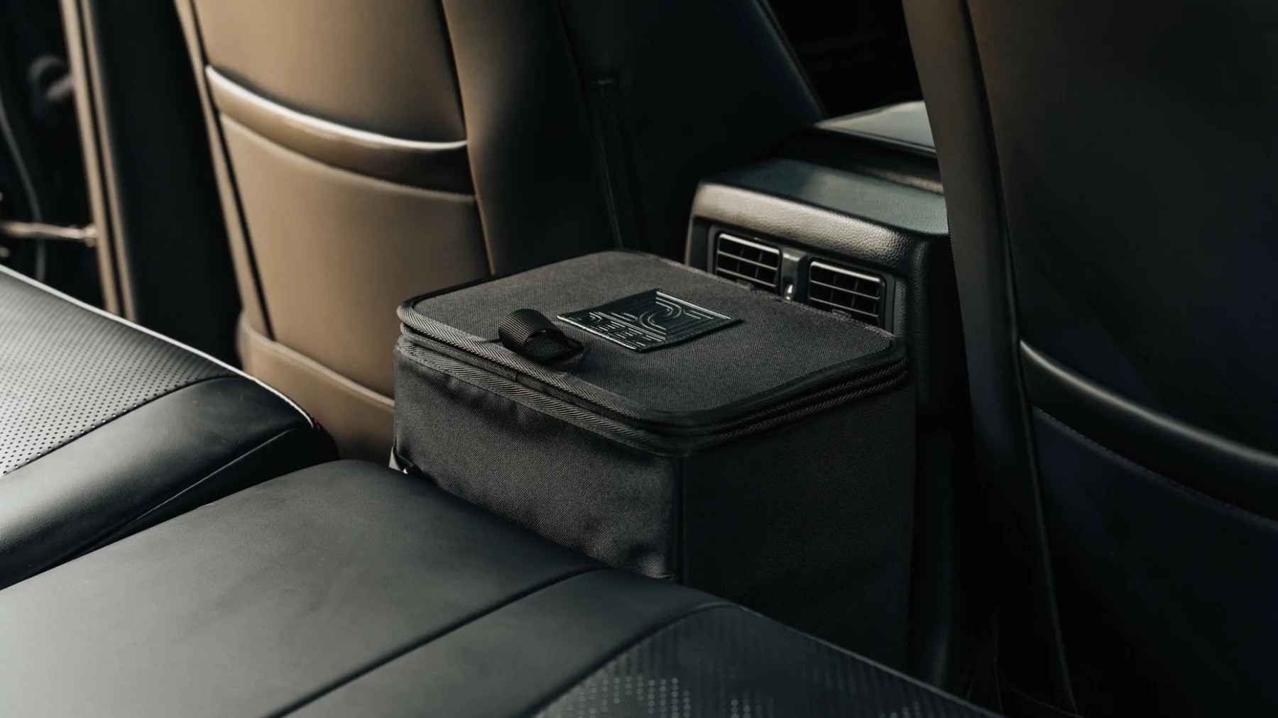 Black Double Deez Goodz car trash can positioned behind the center console between the front seats.