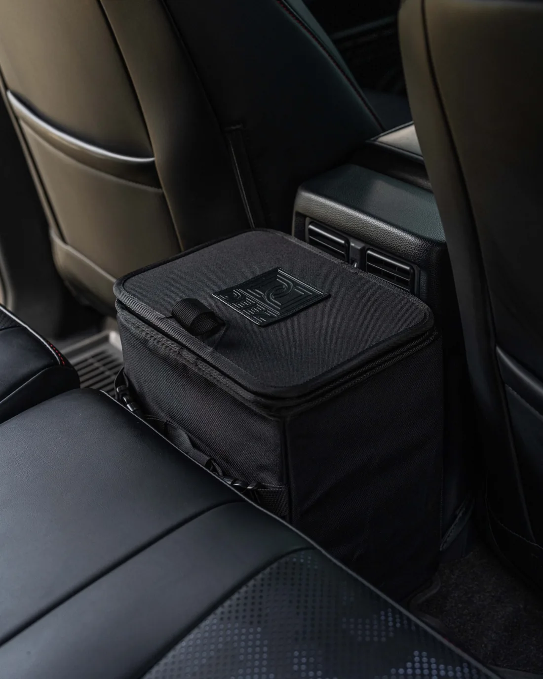 Double Deez Goodz black car trash can with closed lid installed behind the front seats.
